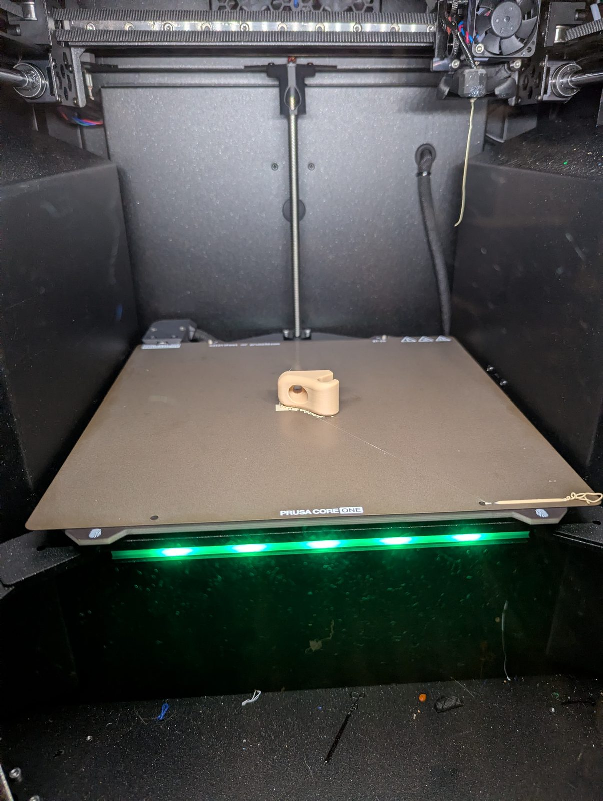 The tan v12 clip on the print bed inside the enclosed printer.