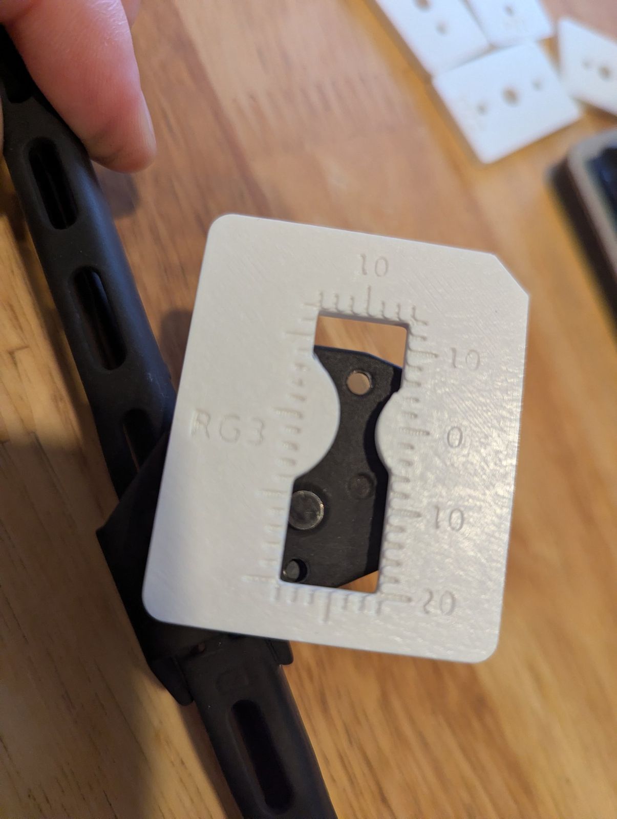 A white printed registration gauge with a numbered window laid over the black stock carrier plate.