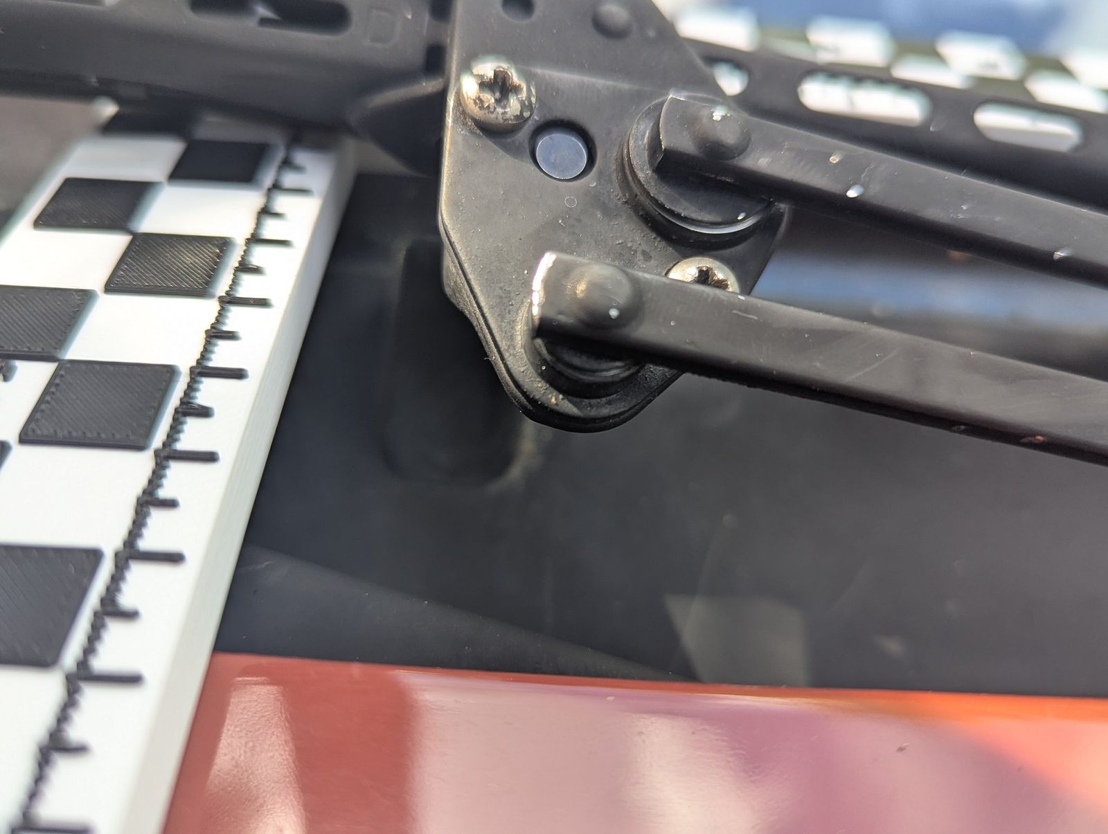 The original driver-side wiper carrier on the end of the arm, next to a scale bar.